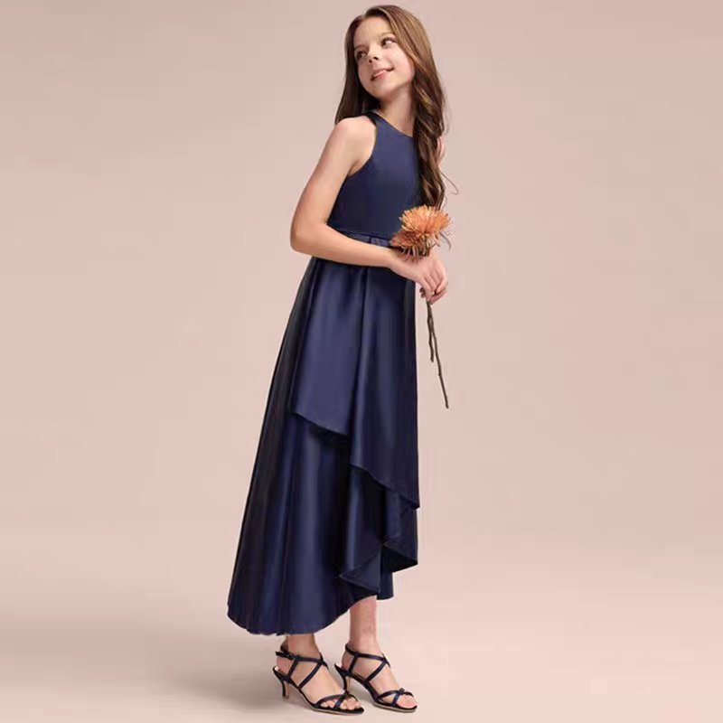 Girl in navy blue sleeveless dress with hi-lo hem, wearing strappy heels and holding a flower.