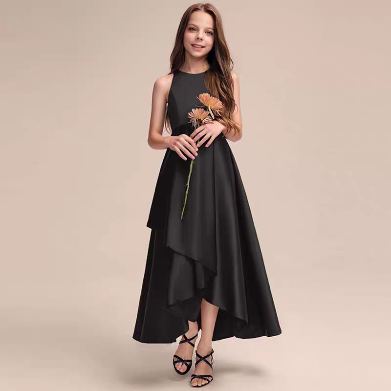 Girl in black halter neck asymmetrical satin dress and black strappy heels holding flowers.