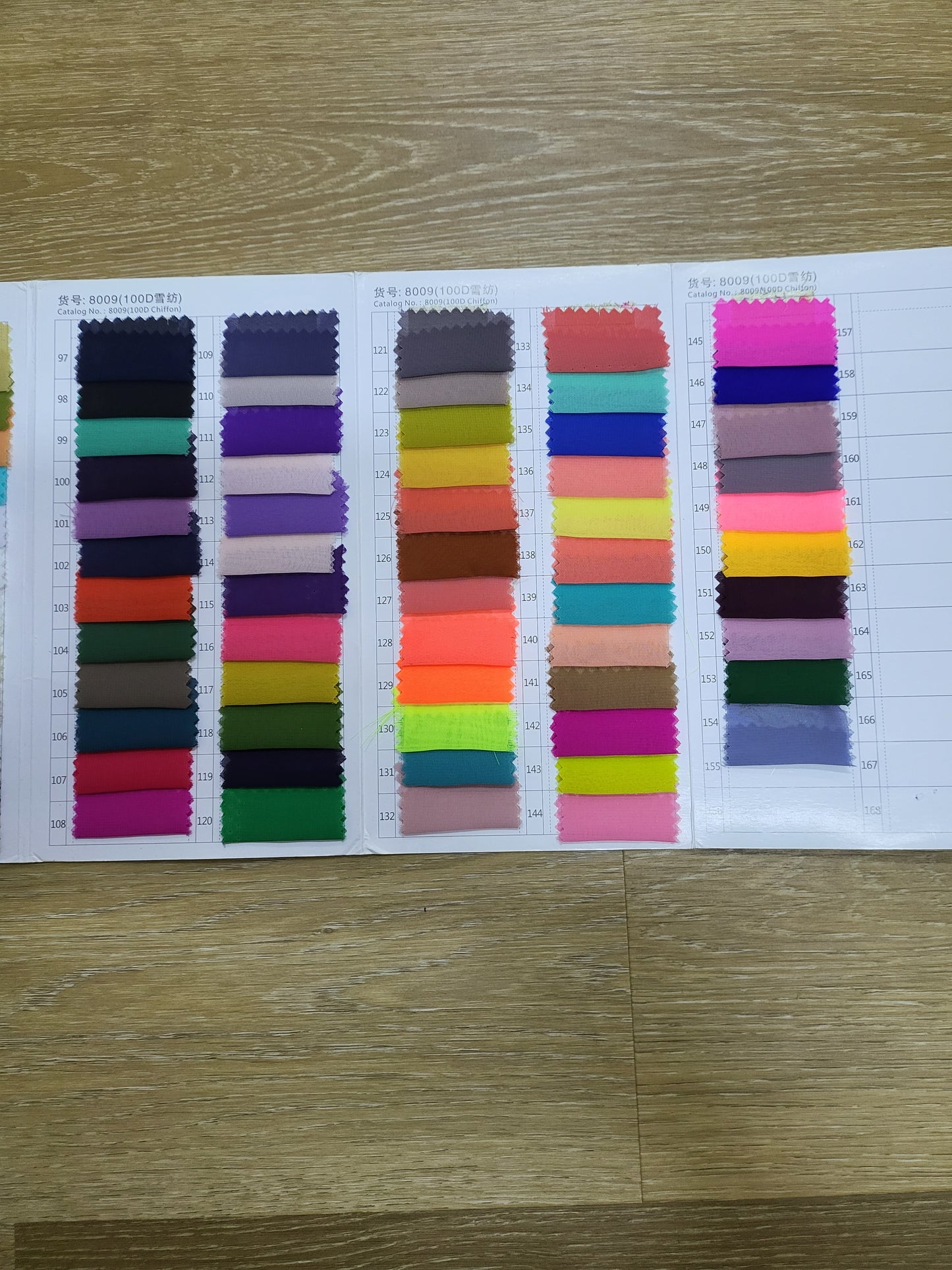 Catalog of 100D chiffon fabric swatches, showing a variety of colors. Catalog No.: 8009. Close-up shot.