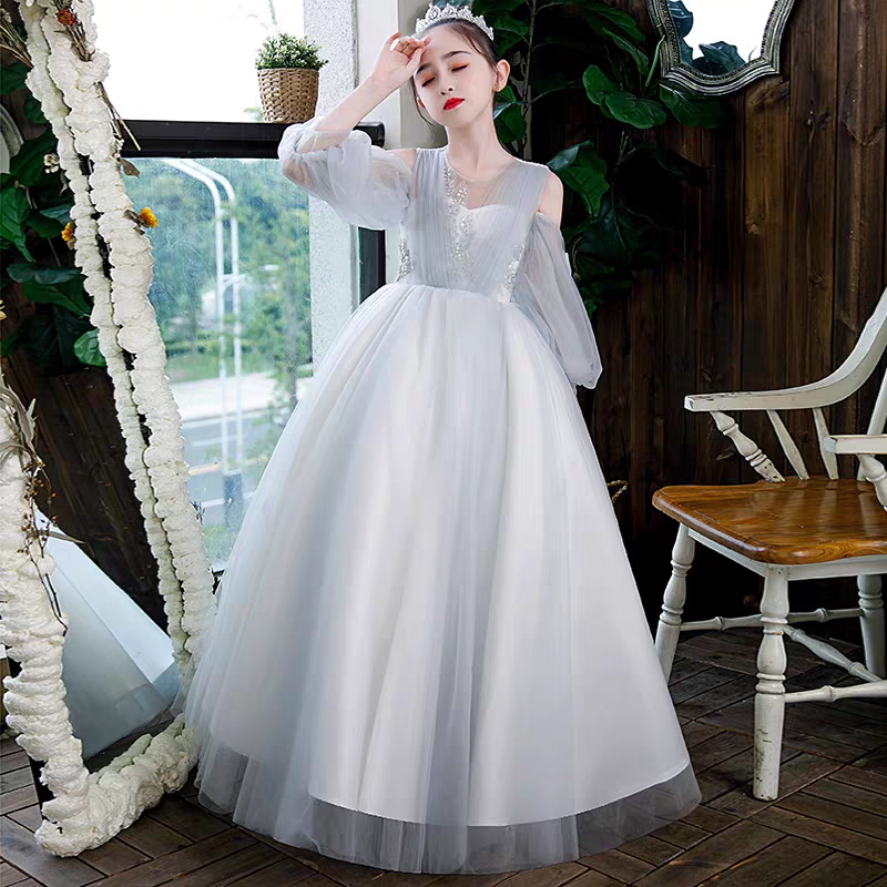 Girl in elegant white formal dress with sheer sleeves and tiara.