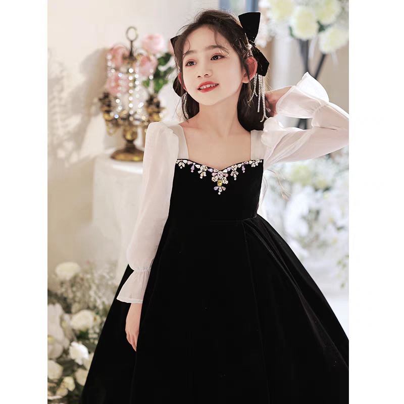 Girl in black velvet dress with sheer sleeves and jewel neckline, formal wear.
