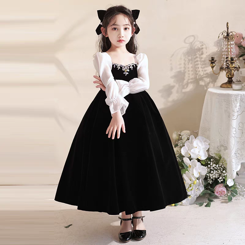 Girl in black velvet party dress with white sleeves and jewel neckline.