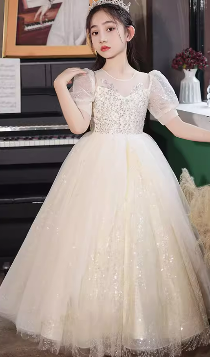 Girl wearing a beautiful, formal ivory dress with sequined bodice and tulle skirt.