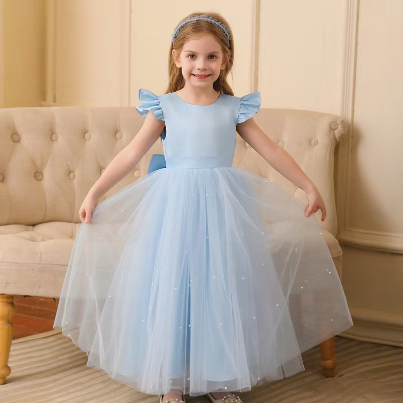 Girl in a light blue formal dress with a tulle skirt and pearl accents, smiling.