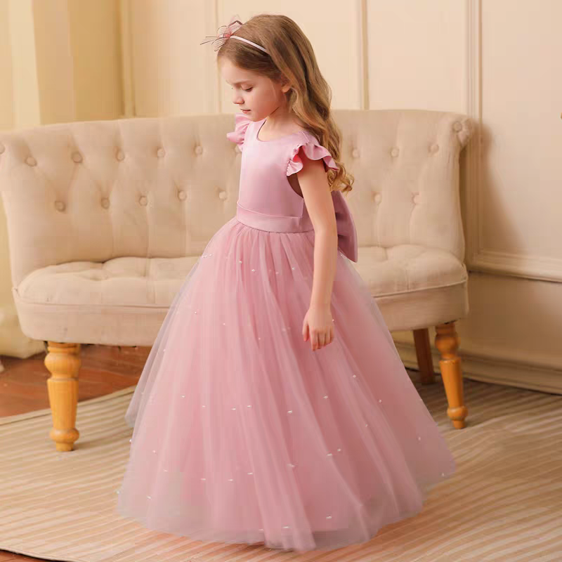 Girl in pink tulle dress with pearl accents and back bow detail.