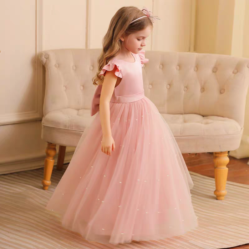 Girl in a pink formal dress with tulle skirt and bow detail.