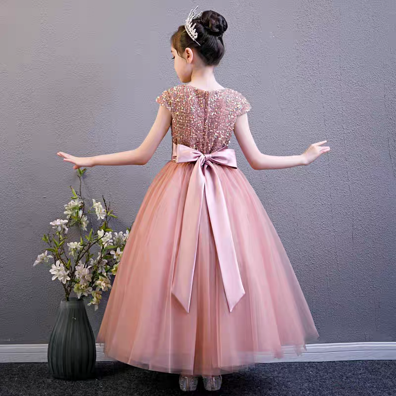 Back view of girl in pink sequin bodice gown with tulle skirt and satin bow.