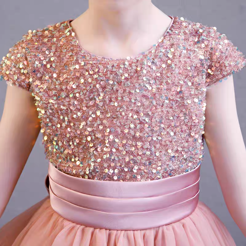 Close-up of a pink sequined bodice girl's dress with a satin sash.