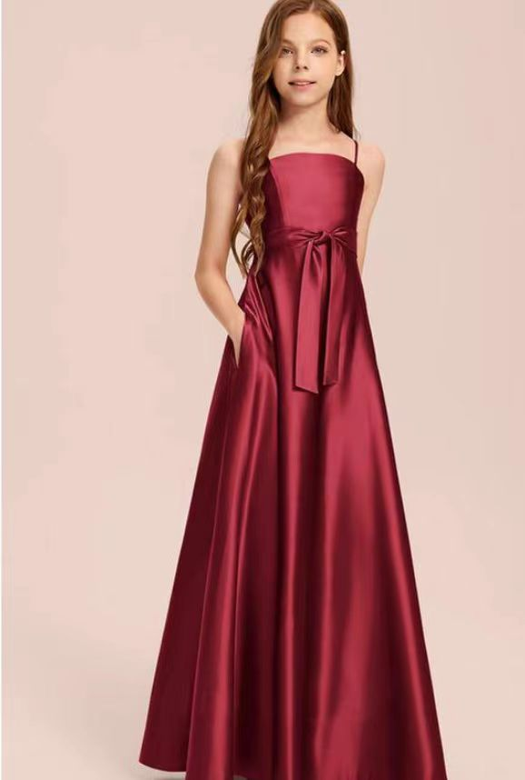Girl wearing a burgundy formal dress with spaghetti straps and a tie waist.