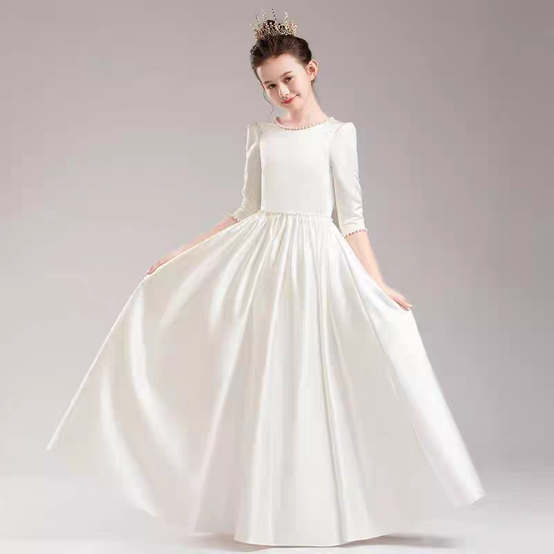 Girl in a white satin gown with pearl trim and a crown, posing with the skirt flared out.