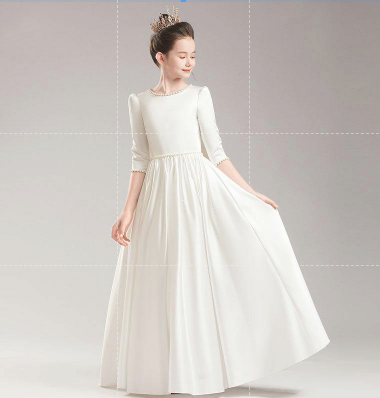 Girl in long white satin dress with pearl accents and crown.