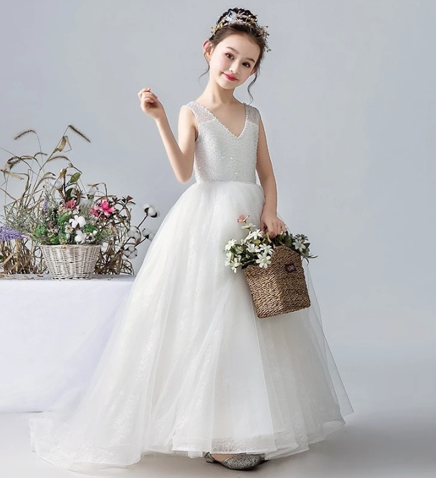 Girl in white sequin V-neck tulle flower girl dress holding flower basket.