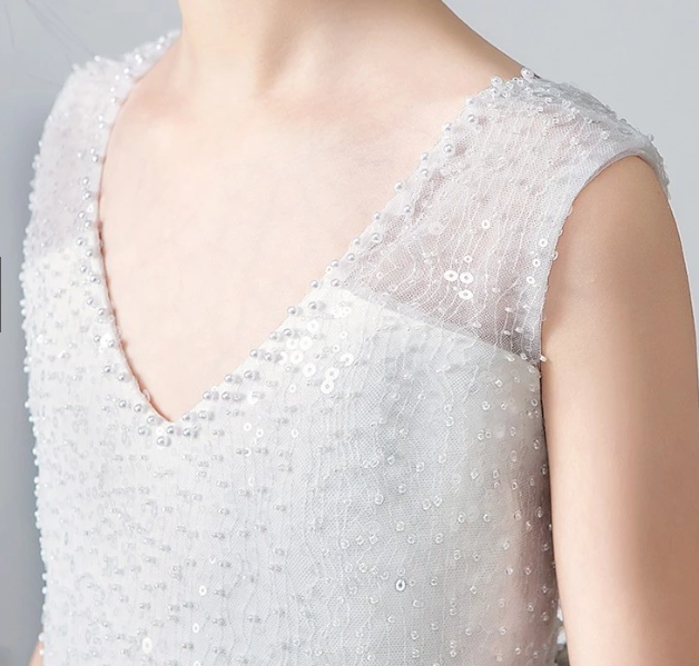 Close-up of a white sequined V-neck formal dress with cap sleeves.