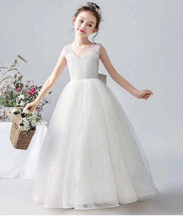 Girl in white formal dress with V-neck and tulle skirt holding flower basket.