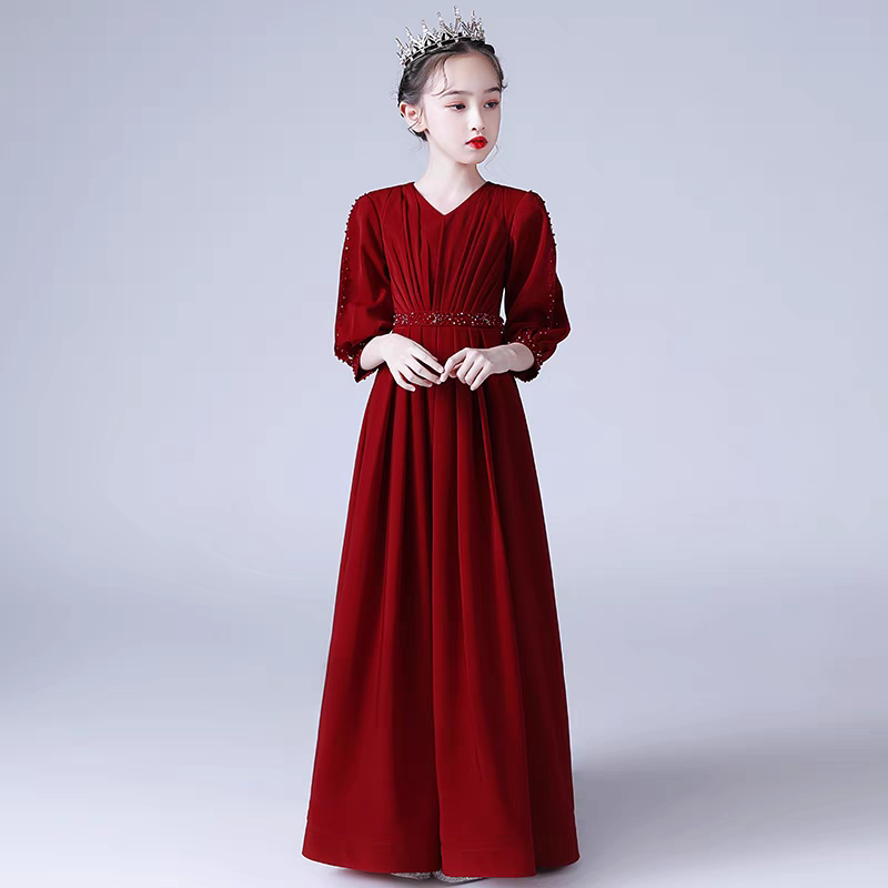 Girl in a long red formal dress with v-neck, beaded sleeves and waistline, wearing a tiara.