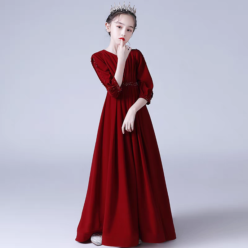 Girl in a long sleeve red gown with beaded details and tiara.