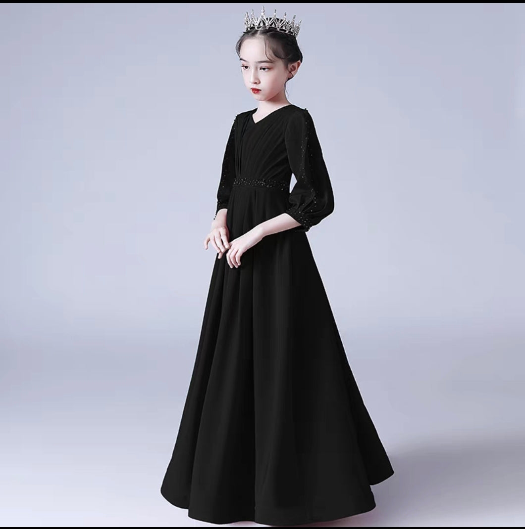 Girl in long black formal dress with sleeves and tiara, perfect for special occasions.