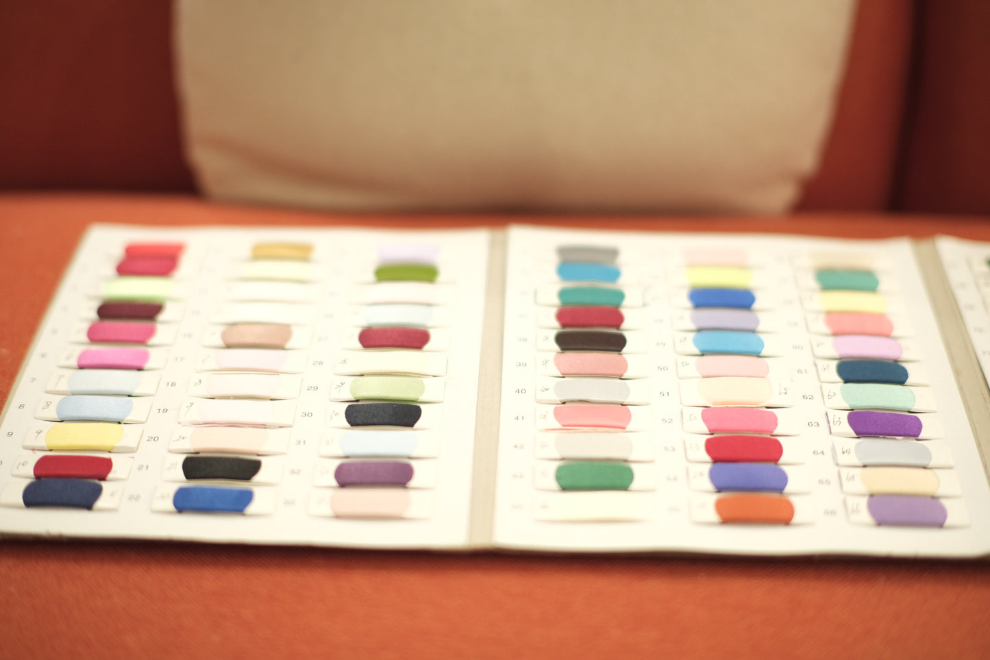 Open fabric swatch book with various colorful textile samples for sewing projects.
