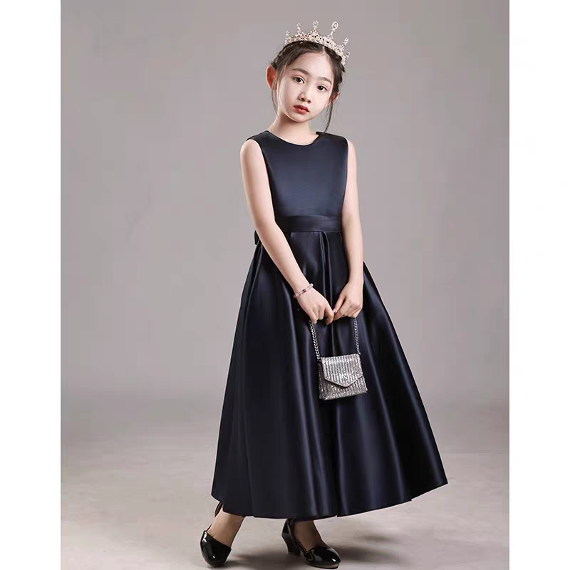 Girl in navy satin dress with tiara and small purse.