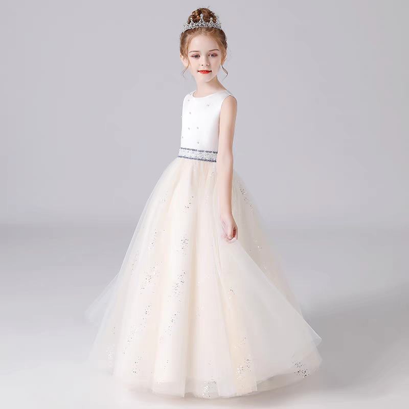 Girl in sleeveless cream-colored formal dress with glittery tulle skirt and tiara.
