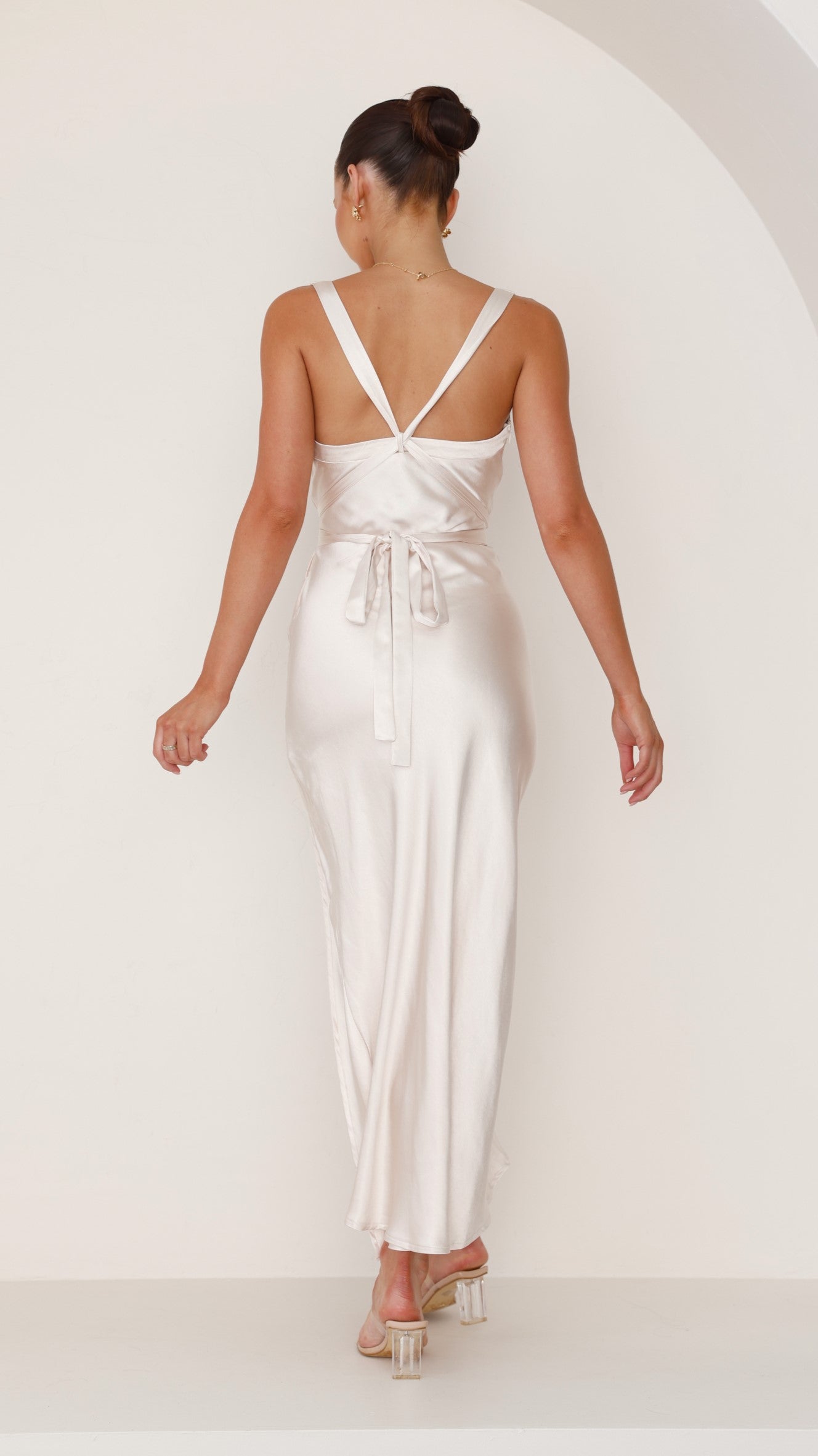 Back view of a champagne-colored maxi dress with straps and tie-back detail.