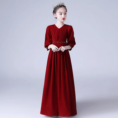 Girl in a long red formal dress with v-neck, beaded sleeves and waistline, wearing a tiara.