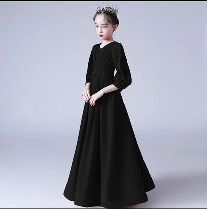 Girl in long black formal dress with sleeves and tiara, perfect for special occasions.